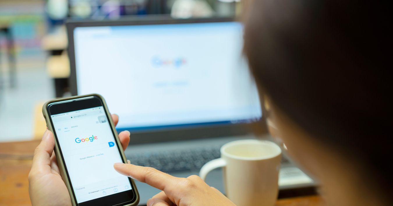 Person Using Google on their Mobile Phone and Laptop