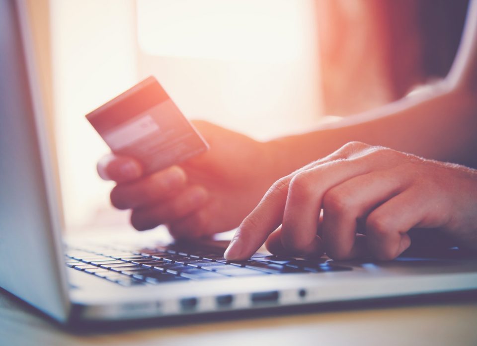 Close up of hands on a laptop with credit card in hand